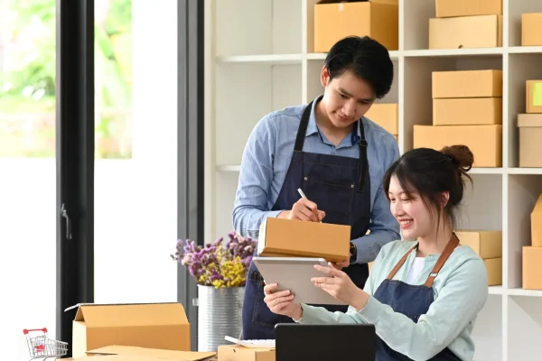 Start up business people working in modern home office and prepa Start Up Business People Working In Modern Home Office And Preparing Parcel For Delivery. Online Selling, E-Commerce Concept.